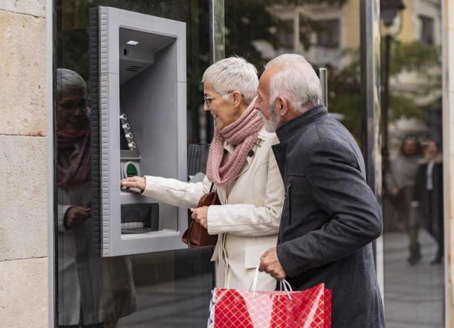 Two people inserting a card at a cash machine