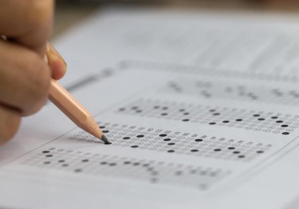 Education school test concept : Hands student holding pencil for testing exams writing answer sheet or exercise for taking fill in admission exam multiple carbon paper computer at university classroom