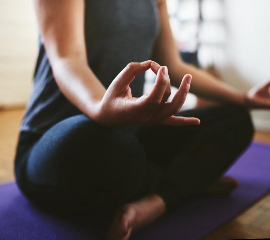Cropped shot of an unrecognizable woman sitting on a yoga mat and meditating alone in her home