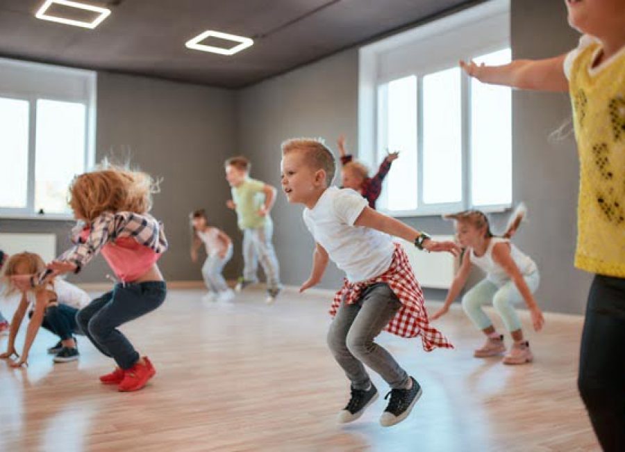 Group of cute little boys and girls studying modern dance in studio. Children jumping while having a choreography class. Sport. Active lifestyle