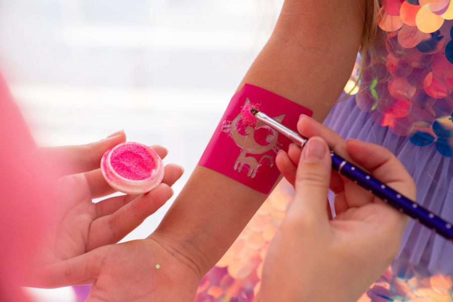 the child makes a temporary tattoo of a kitten with pink sequins. decorative cosmetics for children and adults. shop.