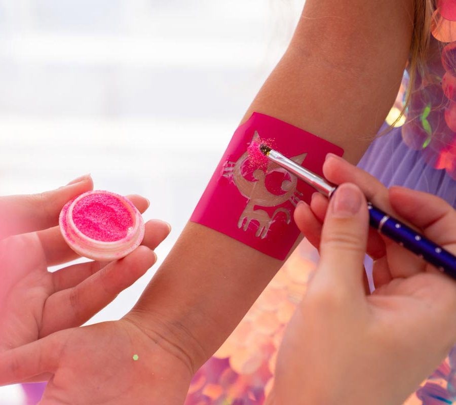the child makes a temporary tattoo of a kitten with pink sequins. decorative cosmetics for children and adults. shop.