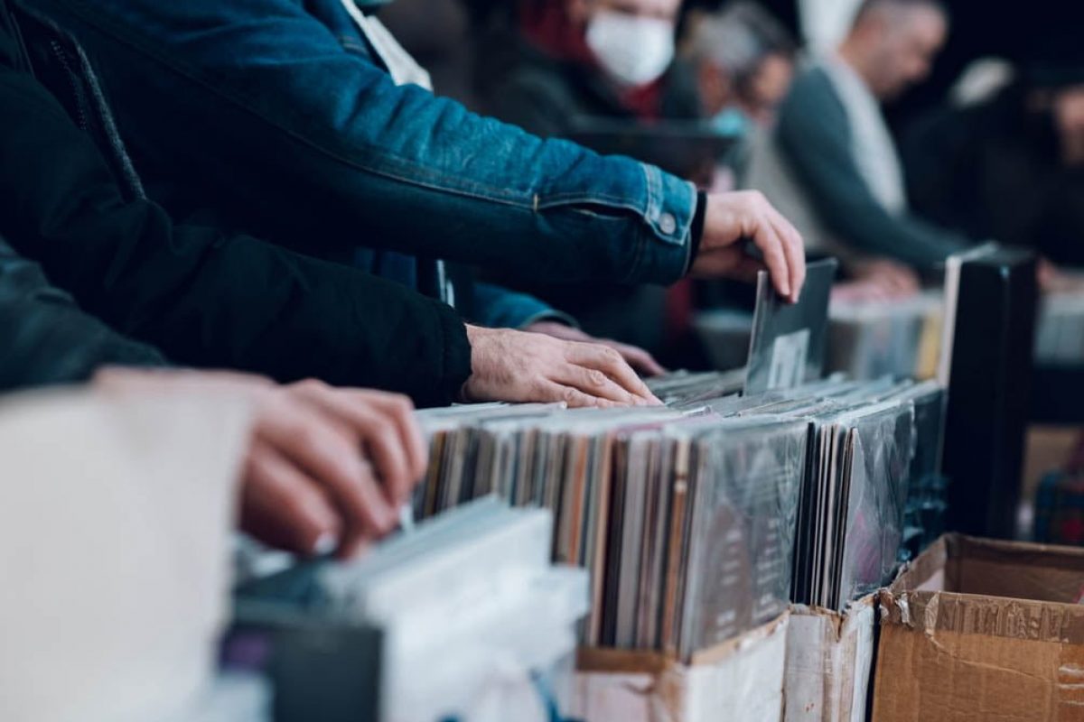 Close-up of a man hands choosing a vinyl at the vinyl market. Choosing vinyl records in store. Records on sale in a vintage vinyl shop.