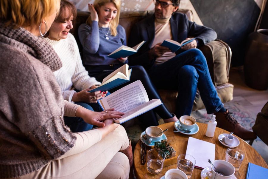 Mature book club members are discussing a book in a café over drinks