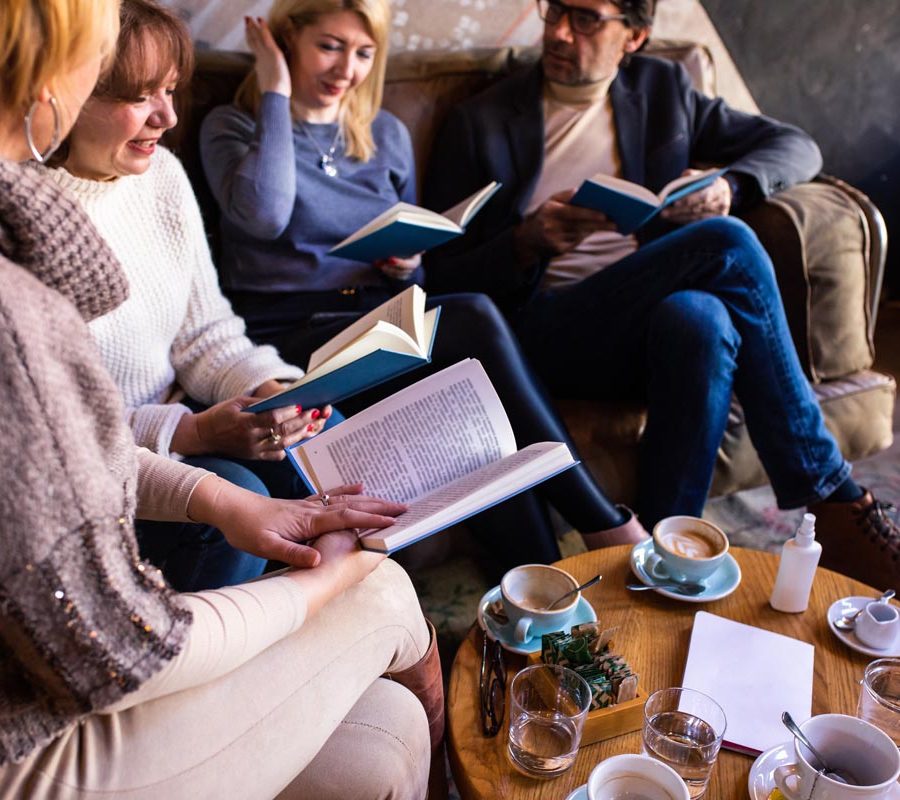 Mature book club members are discussing a book in a café over drinks