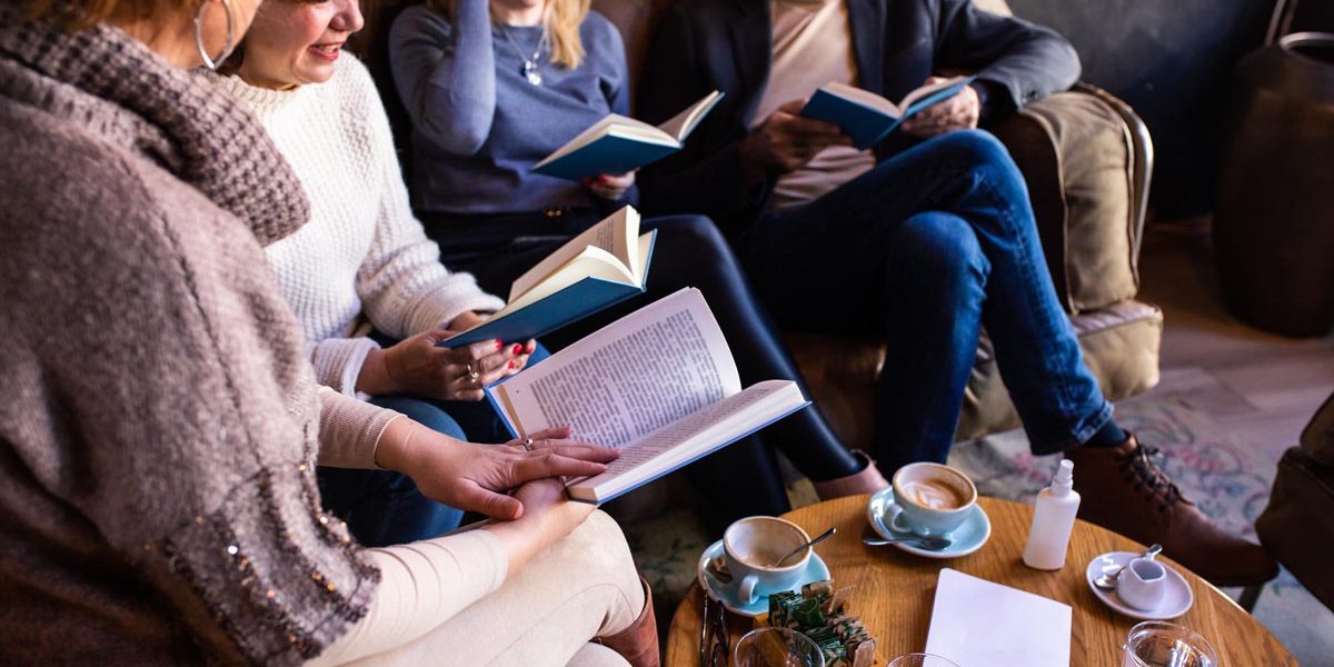 Mature book club members are discussing a book in a café over drinks