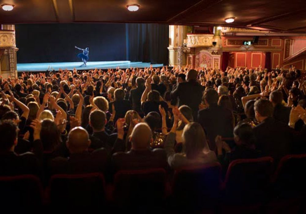 Audience applauding ballerina on stage in theater