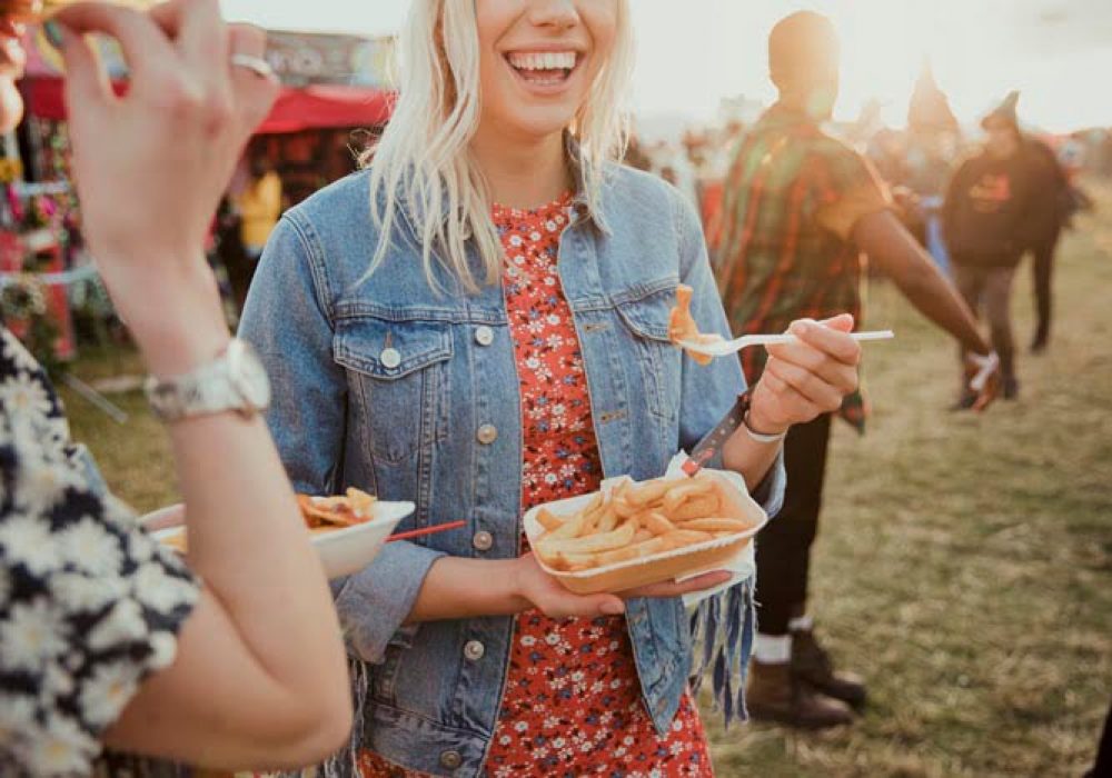 Group of friends eating food at a music festival.