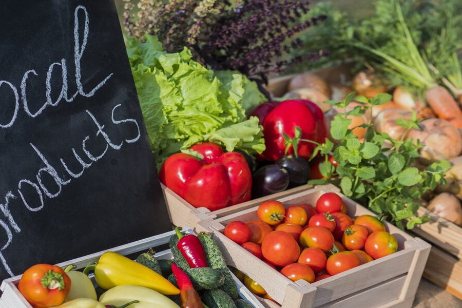 Counter with fresh vegetables and a sign of local products.