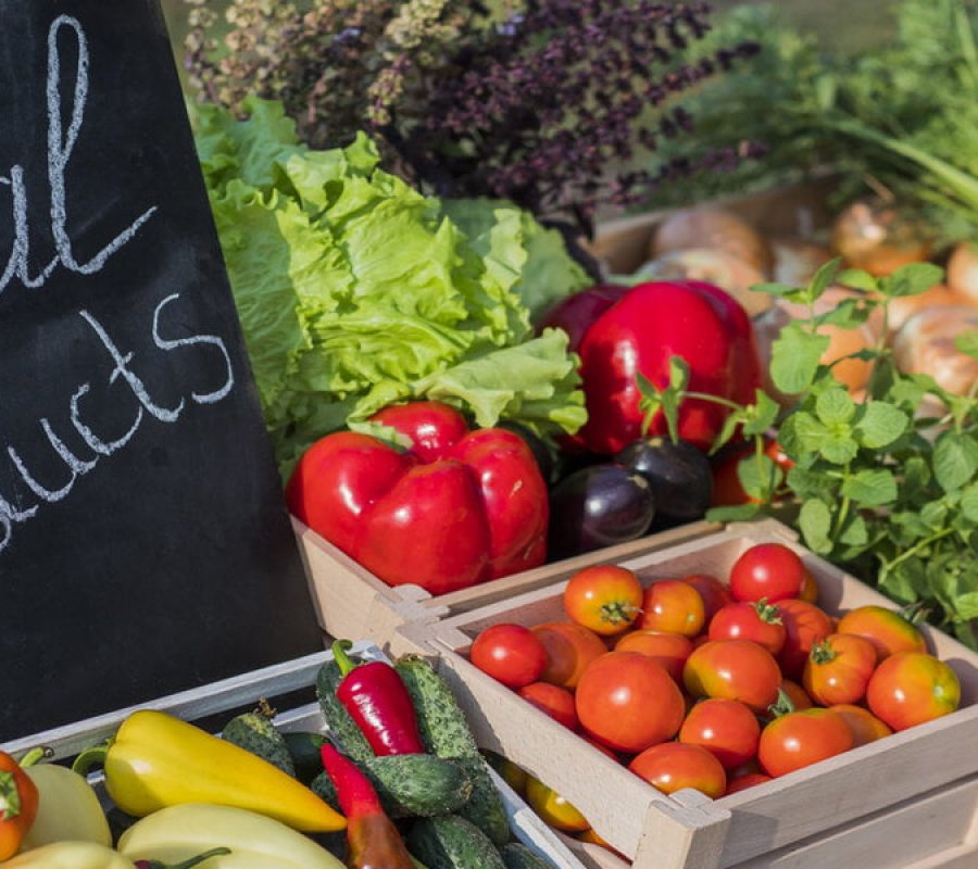 Counter with fresh vegetables and a sign of local products.