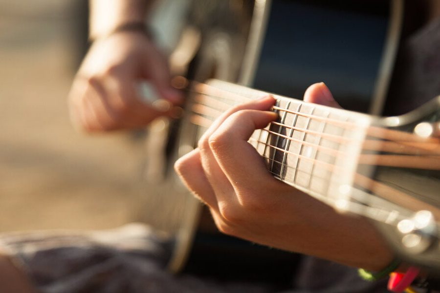 Teen girl playing acoustic guitar, detail, shallow DOF.
