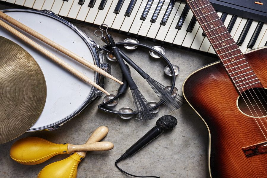 a group of musical instruments including a guitar, drum, keyboard, tambourine.