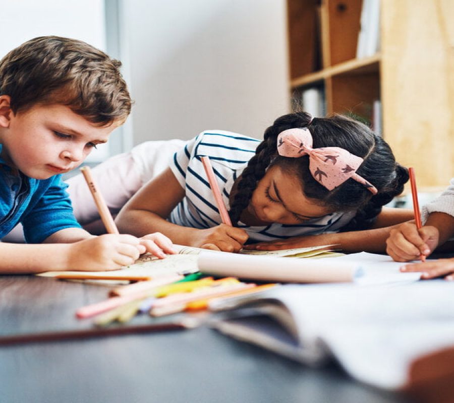 Cropped shot of kids coloring in while lying on the floor