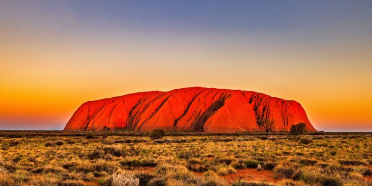 Uluru,At,Sunset,With,Vibrant,Orange,Hues,And,A,Clear